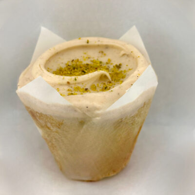 Baked & Wired Vanilla cake with ground pistachios, honey-cardamom cream cheese buttercream, topped with crushed pistachios.